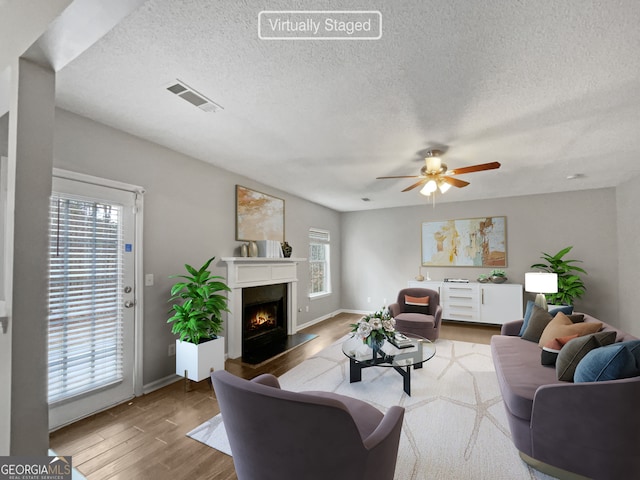 living room featuring a textured ceiling, hardwood / wood-style flooring, a healthy amount of sunlight, and ceiling fan