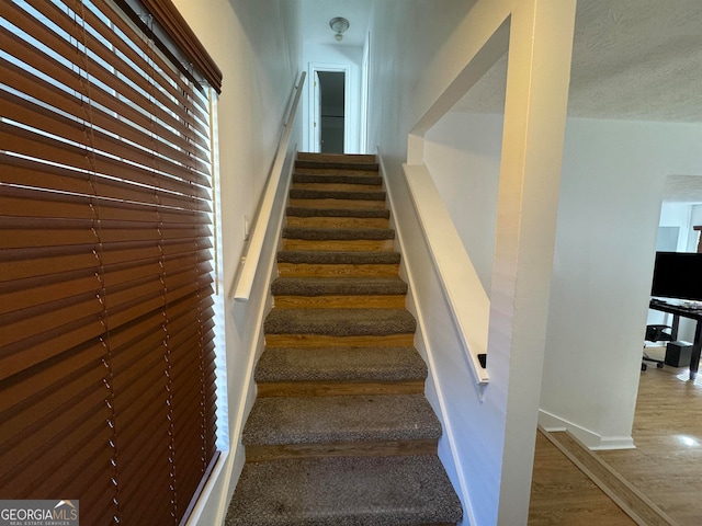 stairs featuring a textured ceiling and dark wood-type flooring