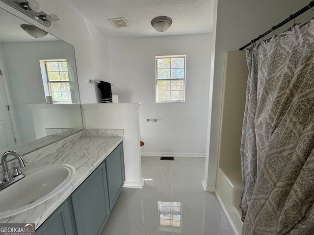 bathroom featuring tile flooring, shower / bathtub combination with curtain, large vanity, and a textured ceiling