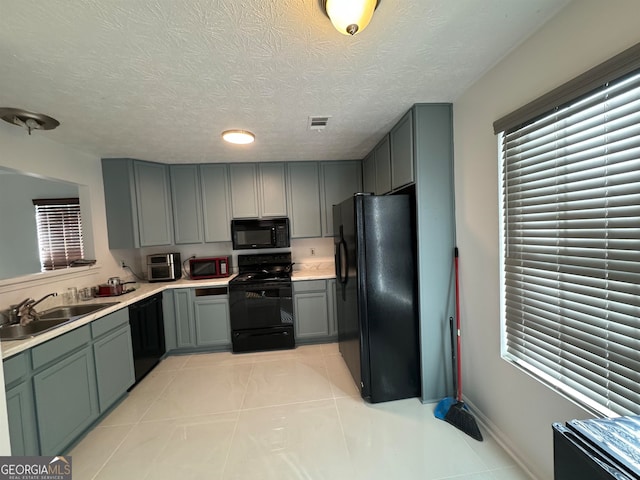 kitchen featuring a textured ceiling, light tile flooring, sink, and black appliances