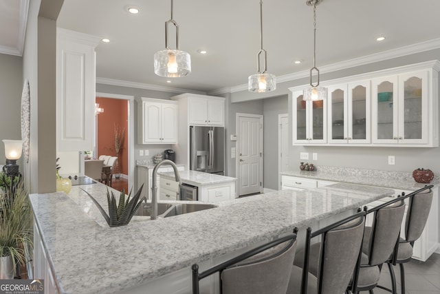 kitchen with sink, stainless steel fridge with ice dispenser, a kitchen island, white cabinets, and decorative light fixtures