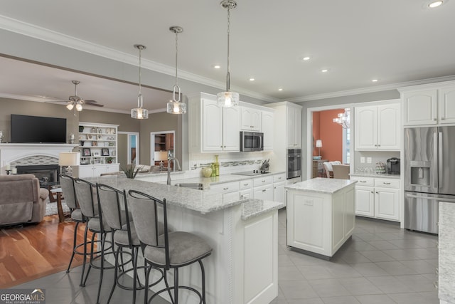 kitchen featuring light tile floors, ceiling fan with notable chandelier, appliances with stainless steel finishes, white cabinets, and hanging light fixtures