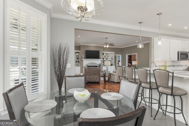 dining space with ceiling fan with notable chandelier, hardwood / wood-style flooring, and ornamental molding