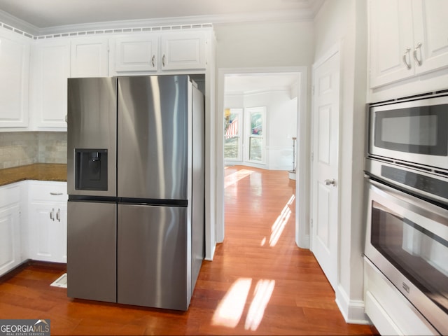 kitchen with dark wood-type flooring, crown molding, stainless steel appliances, and white cabinetry