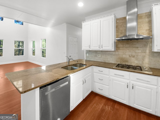 kitchen with appliances with stainless steel finishes, tasteful backsplash, dark wood-type flooring, kitchen peninsula, and wall chimney exhaust hood