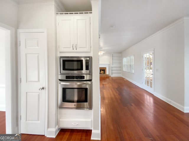 kitchen featuring dark hardwood / wood-style floors, white cabinetry, appliances with stainless steel finishes, and crown molding