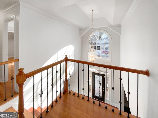 staircase with ornamental molding, light hardwood / wood-style floors, and an inviting chandelier