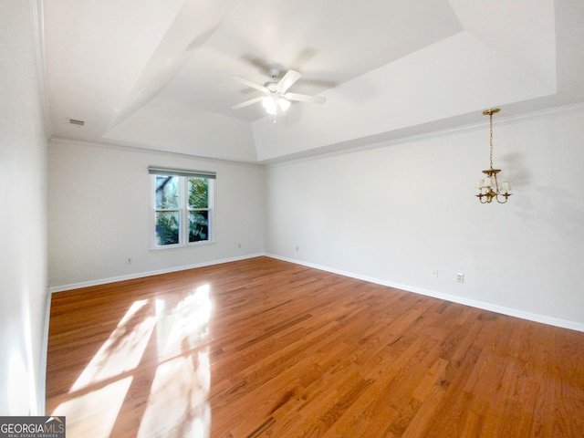 unfurnished room with hardwood / wood-style floors, a tray ceiling, and ceiling fan with notable chandelier