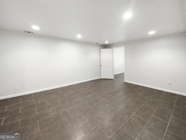 spare room featuring crown molding and dark tile flooring