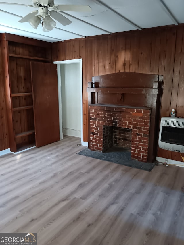 unfurnished living room featuring a fireplace, wood walls, ceiling fan, and dark hardwood / wood-style flooring