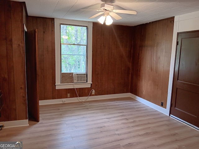unfurnished room with ceiling fan, wooden walls, and light hardwood / wood-style flooring