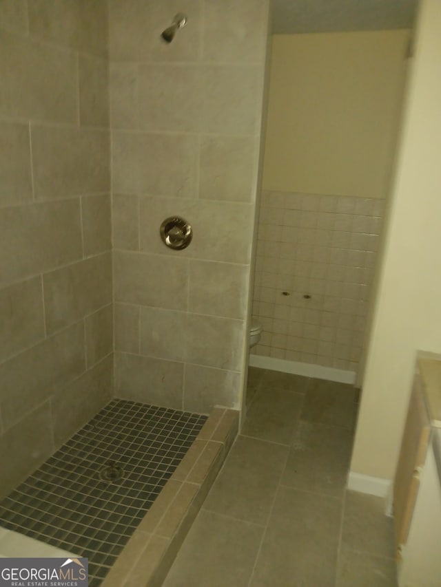 bathroom with toilet, a tile shower, and vanity