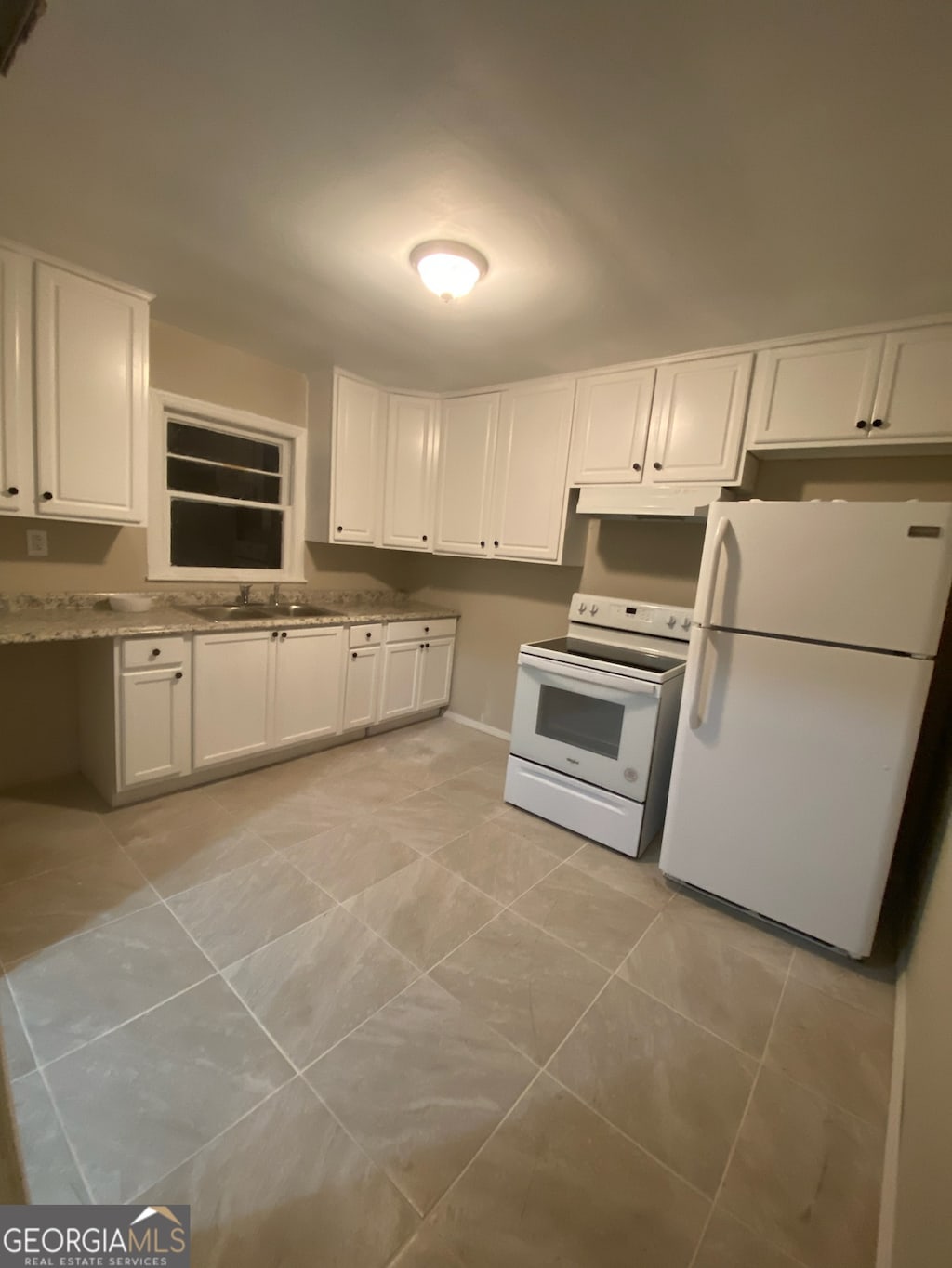 kitchen with light stone counters, white cabinetry, light tile floors, white appliances, and sink