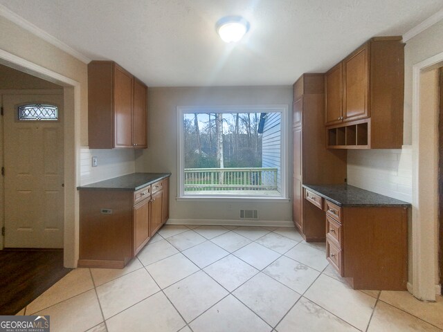 kitchen with light tile floors, crown molding, a wealth of natural light, and backsplash