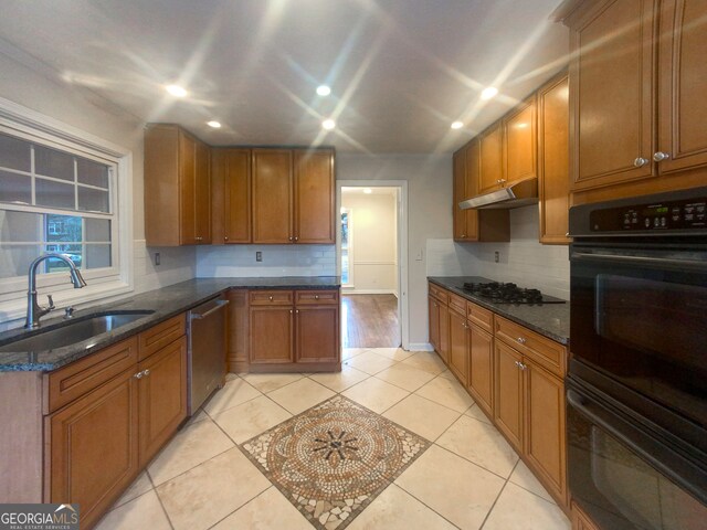 kitchen featuring black appliances, dark stone countertops, backsplash, sink, and light tile flooring