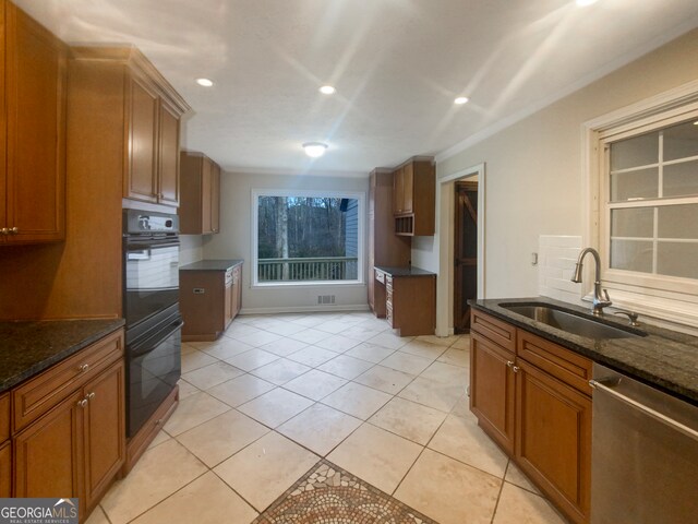 kitchen featuring stainless steel dishwasher, sink, dark stone counters, and black double oven