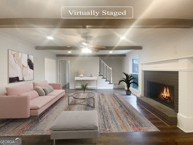 living room with dark hardwood / wood-style floors, beam ceiling, ceiling fan, and a fireplace