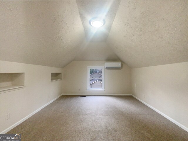 bonus room featuring lofted ceiling, a textured ceiling, carpet flooring, and a wall mounted air conditioner