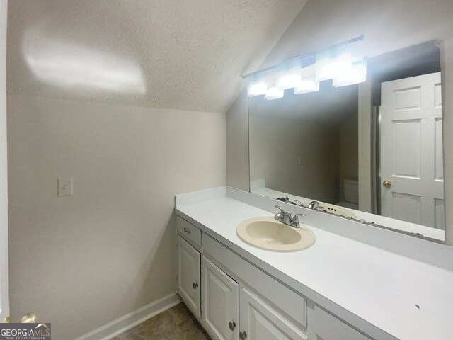 bathroom with lofted ceiling, tile flooring, a textured ceiling, and vanity with extensive cabinet space