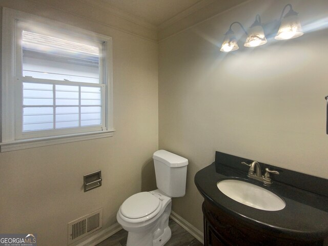 bathroom featuring crown molding, toilet, hardwood / wood-style floors, and vanity