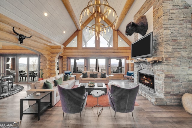 living room featuring beamed ceiling, a fireplace, a chandelier, and rustic walls