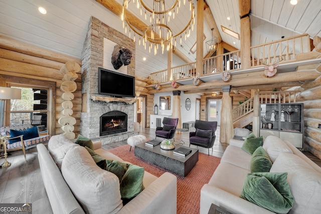 living room with hardwood / wood-style flooring, a stone fireplace, rustic walls, and a notable chandelier