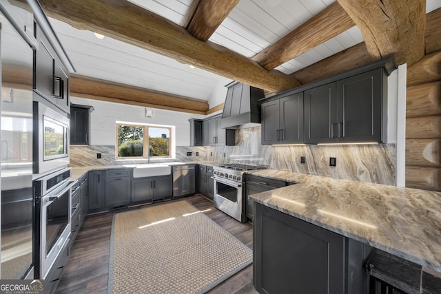 kitchen featuring appliances with stainless steel finishes, sink, tasteful backsplash, wall chimney range hood, and beam ceiling