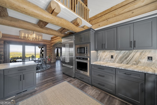 kitchen with tasteful backsplash, dark hardwood / wood-style flooring, beam ceiling, rustic walls, and built in appliances