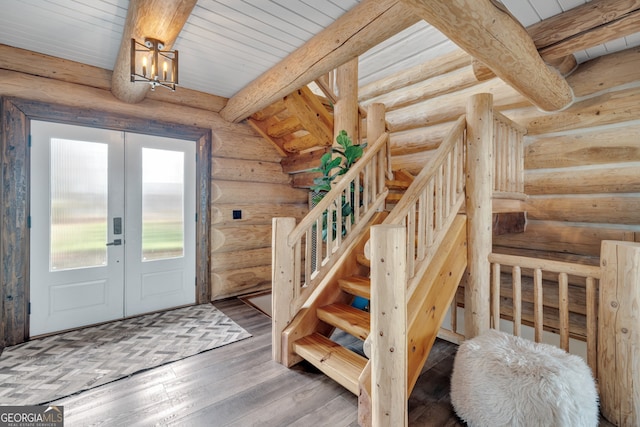 entrance foyer with french doors, rustic walls, dark hardwood / wood-style floors, beam ceiling, and a chandelier