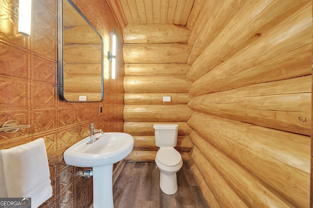 bathroom featuring log walls, vaulted ceiling, toilet, wooden ceiling, and hardwood / wood-style flooring