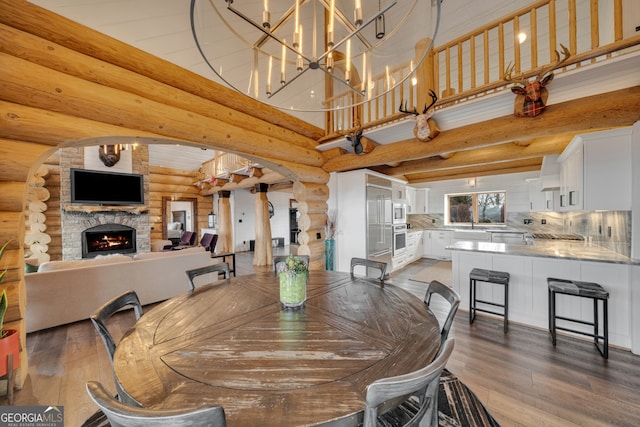 dining area with a chandelier, rustic walls, wood-type flooring, and a fireplace