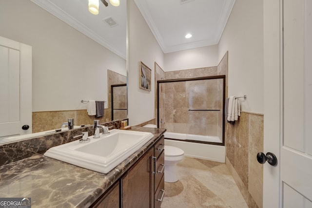 full bathroom with bath / shower combo with glass door, toilet, vanity with extensive cabinet space, tile floors, and ornamental molding