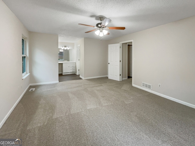 unfurnished bedroom featuring carpet flooring, connected bathroom, a textured ceiling, and ceiling fan