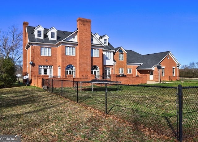 rear view of house with a trampoline and a yard