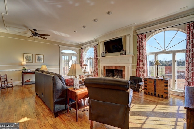 living room featuring light hardwood / wood-style floors, a fireplace, ceiling fan, and a wealth of natural light