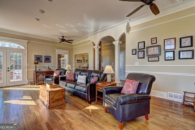 living room with ornate columns, light wood-type flooring, ceiling fan, crown molding, and french doors