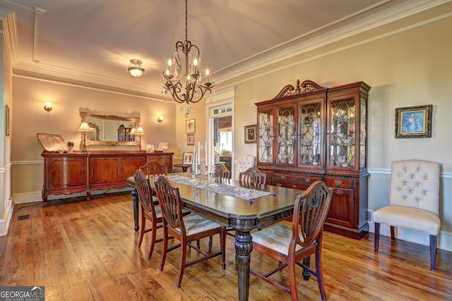 dining area featuring crown molding, a notable chandelier, and hardwood / wood-style flooring