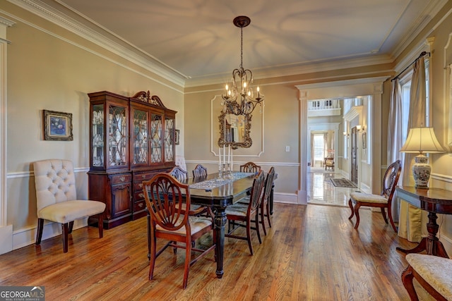 dining area featuring crown molding, a notable chandelier, and hardwood / wood-style flooring