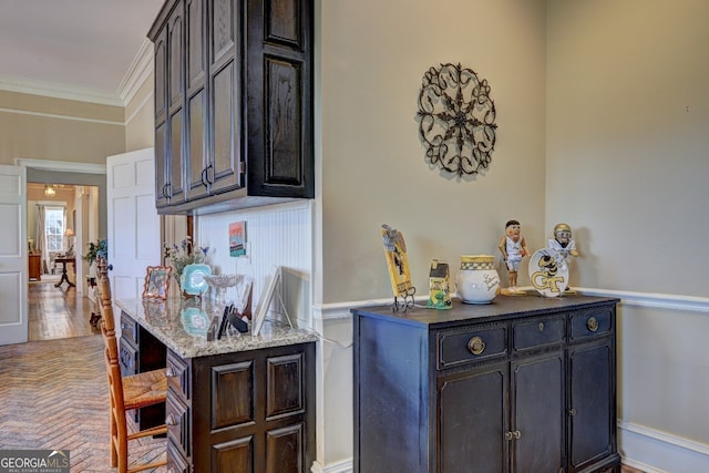 kitchen with light stone counters, dark brown cabinets, and crown molding