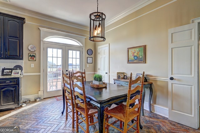 dining space featuring a notable chandelier, dark parquet flooring, ornamental molding, and french doors