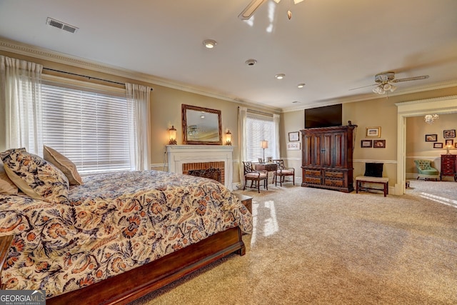 carpeted bedroom featuring a brick fireplace, ceiling fan, and crown molding