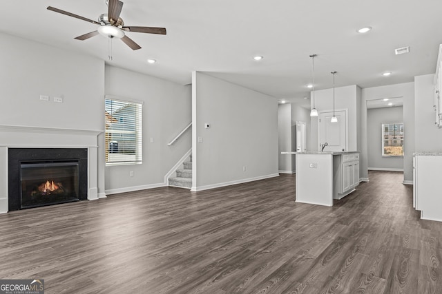 unfurnished living room featuring ceiling fan and dark wood-type flooring