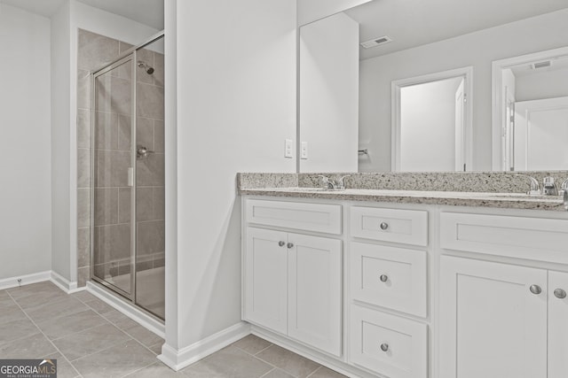 bathroom with dual vanity, tile flooring, and a shower with shower door