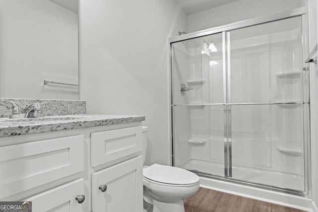 bathroom featuring an enclosed shower, hardwood / wood-style floors, toilet, and vanity with extensive cabinet space