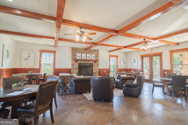 interior space with beamed ceiling, french doors, a stone fireplace, and ceiling fan