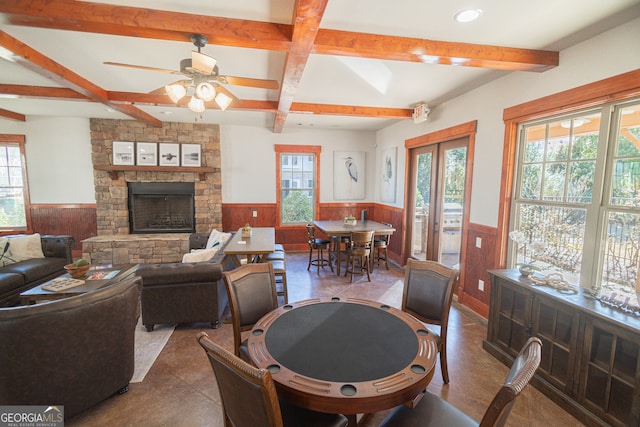 tiled dining area featuring beam ceiling, coffered ceiling, a stone fireplace, and ceiling fan