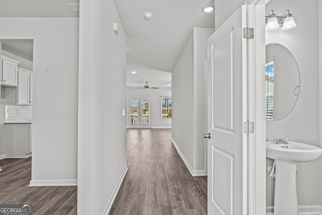 hall with sink, dark hardwood / wood-style floors, and lofted ceiling