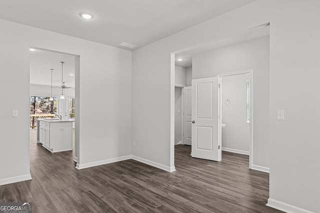 unfurnished bedroom featuring sink, a walk in closet, and dark hardwood / wood-style floors