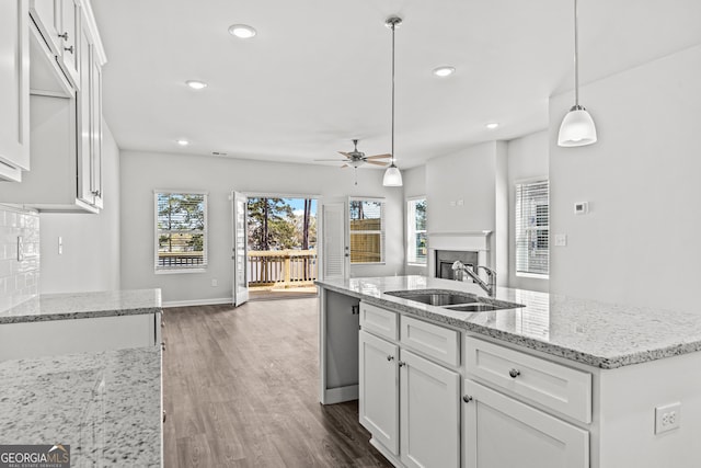 kitchen featuring ceiling fan, pendant lighting, wood-type flooring, sink, and white cabinets