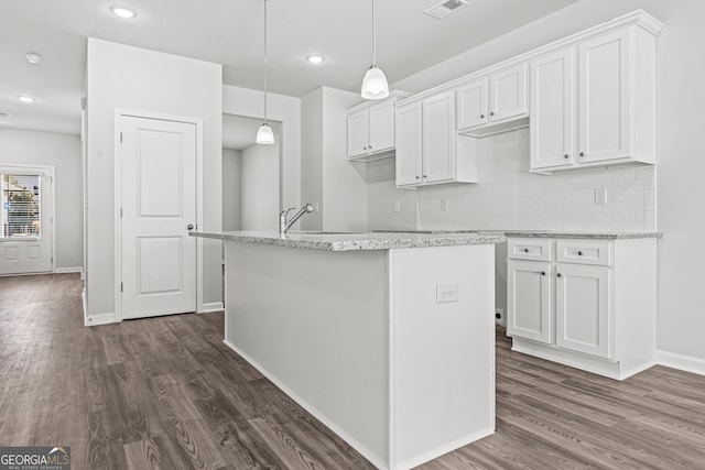 kitchen featuring white cabinetry, a kitchen island with sink, dark wood-type flooring, and tasteful backsplash